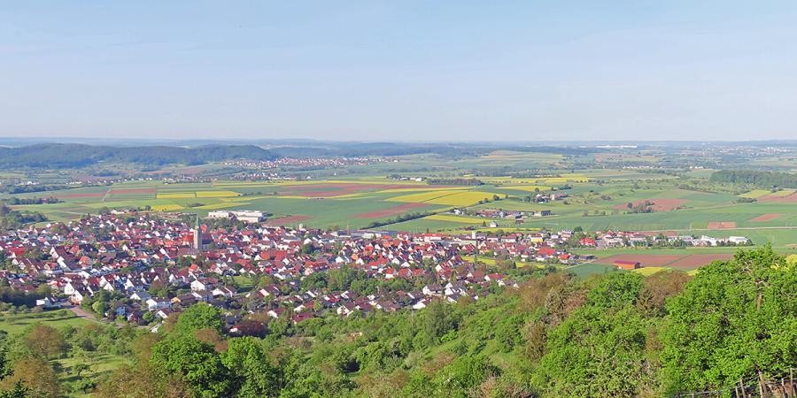 Große Ortschaft, eingebettet in Wald und Kulturlandschaft, im Hintergrund Berge des Schwarzwalds