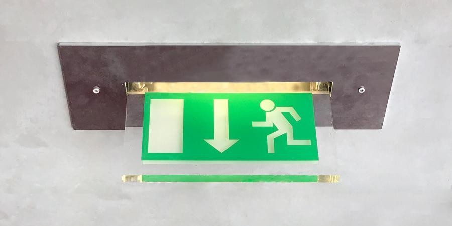Symbolisches Schild für Fluchtweg, an einer Decke angebracht, es zeigt einen laufenden Menschen und einen Pfeil