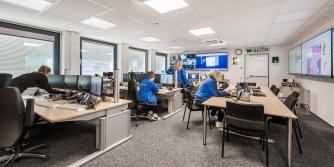 Raum mit mehreren Personen an Computern und Bildschirmen