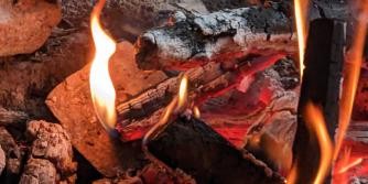 Ausschnitt einer Feuerstelle mit brennendem Holz, Flammen und Glut