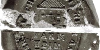 Ausschnitt eines gebrochenen Siegels mit einem abgebildeten Haus auf der oberen Hälfte und der Aufschrift Wankheim auf der unteren Hälfte.