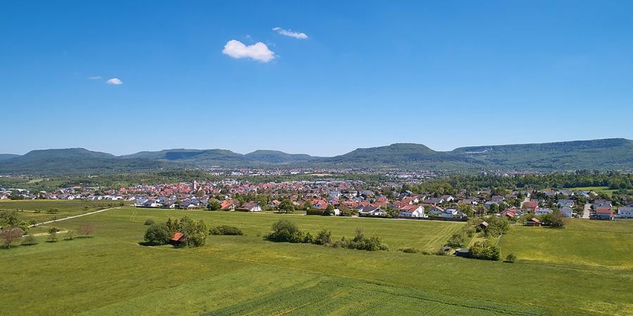 Landwirtschaftliche Flächen, im mittleren Bildbereich die Häuser von Ofterdingen, im Hintergrund die Berge der Schwäbischen Alb