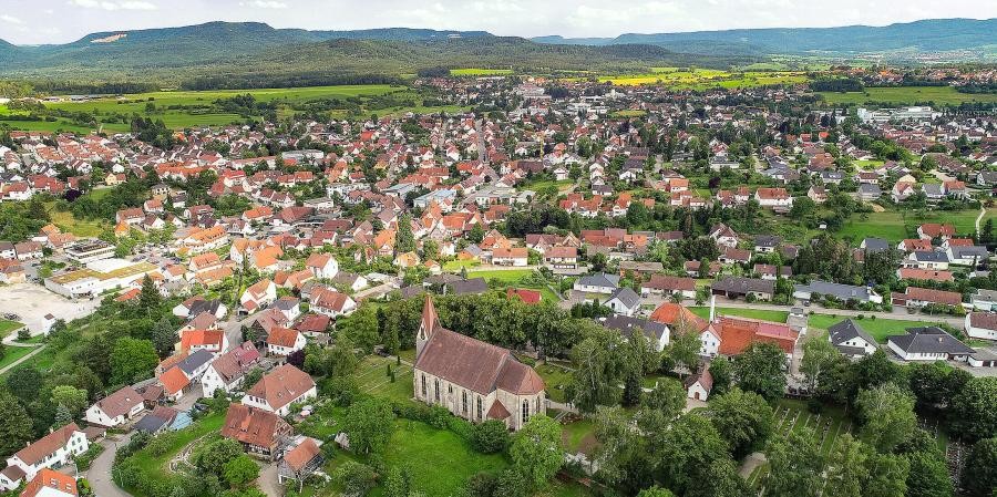Bodelshausen Siedlungsgebiet mit Häusern und Kirche, im Hintergrund die Berge der Schwäbischen Alb