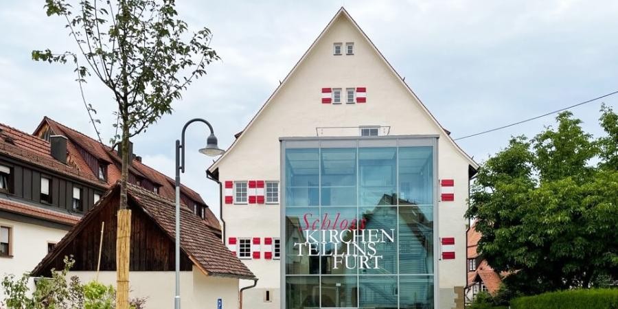 Giebelansicht eines historischen Gebäudes, davor gebaut ein gläserner Kubus mit Beschriftung "Schloss Kirchentellinsfurt"
