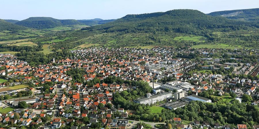 Luftbild der Stadt mit Häusern, im Hintergrund Berge der schwäbischen Alb