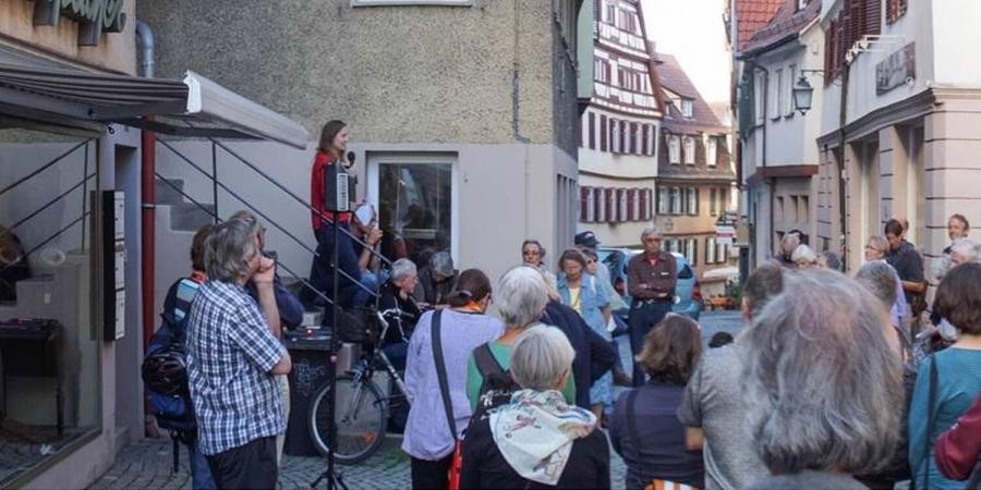 Eine Gruppe von Personen steht in einer Gasse der Tübinger Altstadt, auf einer Treppe steht eine junge Frau die spricht
