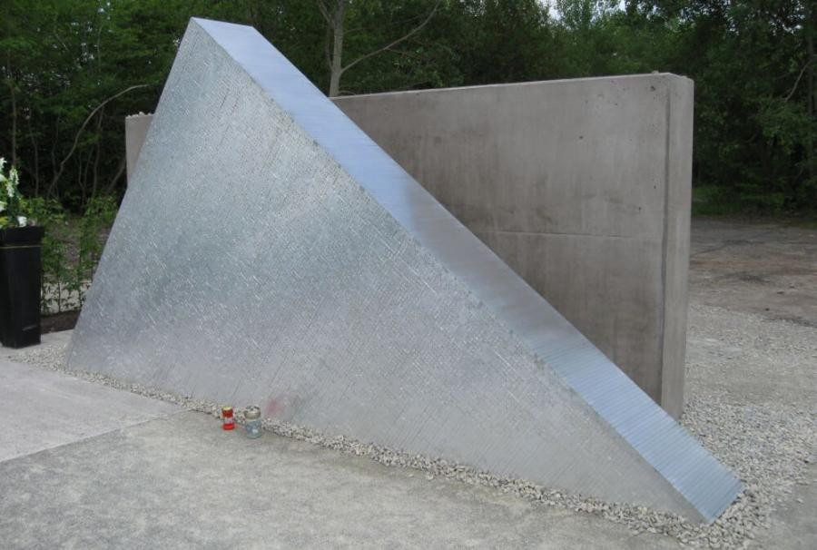 Gedenkstätte Hailfingen-Tailfingen Zwei große Scheiben, eine als Dreieck mit Namen, die dahinter stehende rechtwinklig, Gedenkkerzen stehen davoren