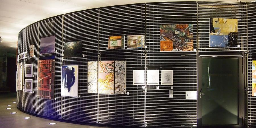 Gebogene Außenwand eines großen Raums, mit einer Ausstellung von Gemälden