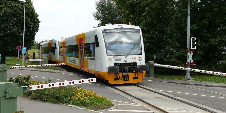 Ein Zug, seitlich beschriftet mit "Schönbuchbahn", fährt an geschlossenen Schranken vorbei