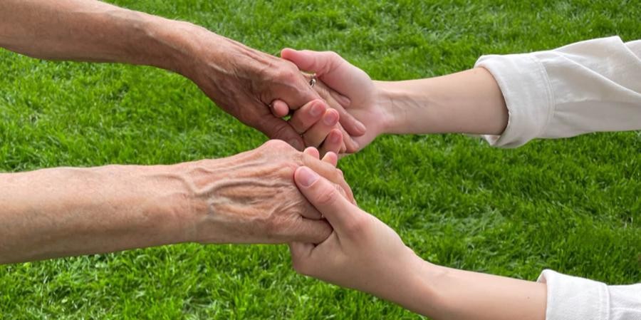 Symbolfoto Pflege, Hände einer jungen Person halten Hände einer alten Person