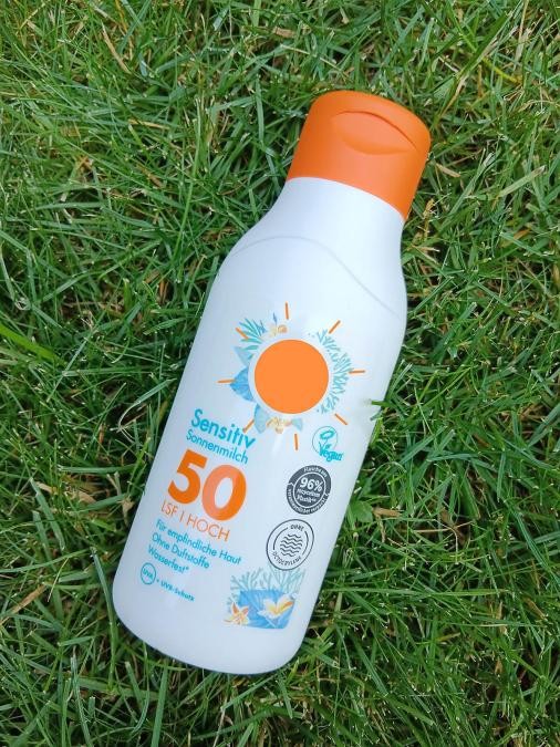 Flasche mit Sonnenmilch liegt im Gras, Aufschrift "Lichtschutzfaktor 50"