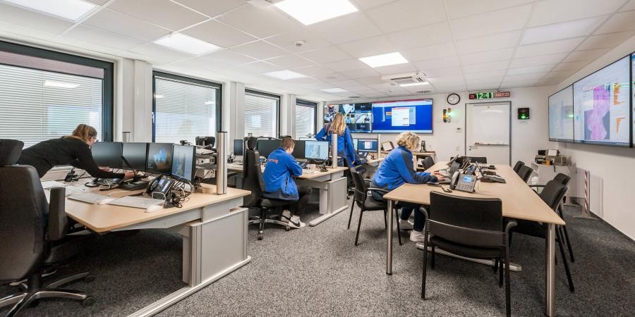 Raum mit mehreren Personen an Computern und Bildschirmen