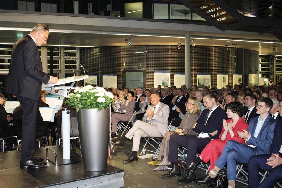 Großer Saal mit zahlreichen Menschen, in Stuhlreihen sitzend, am Rednerpult Landrat Joachim Walter