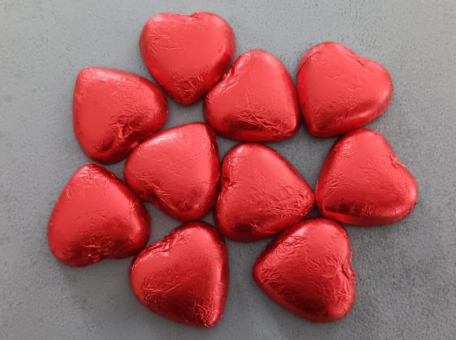Einige Schokoladenherzen in rot glänzendem Papier formen ein Herz