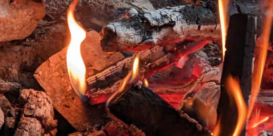 Feuerstelle mit glühendem Holz und Flammen (Ausschnitt)