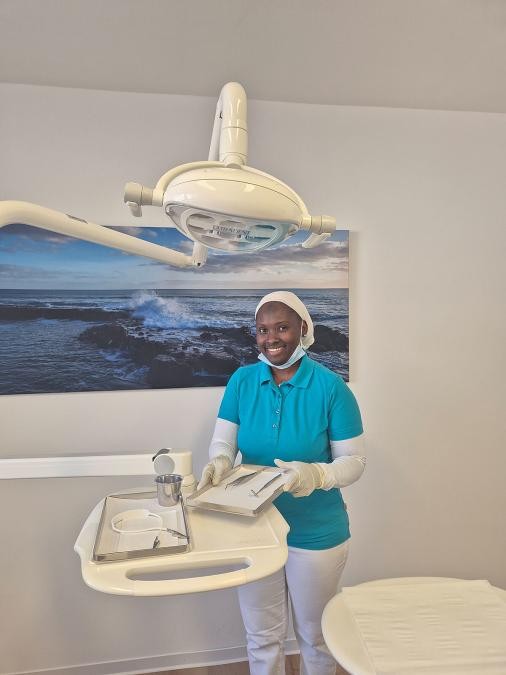 Schwarze Frau in medizinischer Arbeitskleidung an einem Arbeitstisch in einem Arbeitsraum einer Praxis oder Klinik