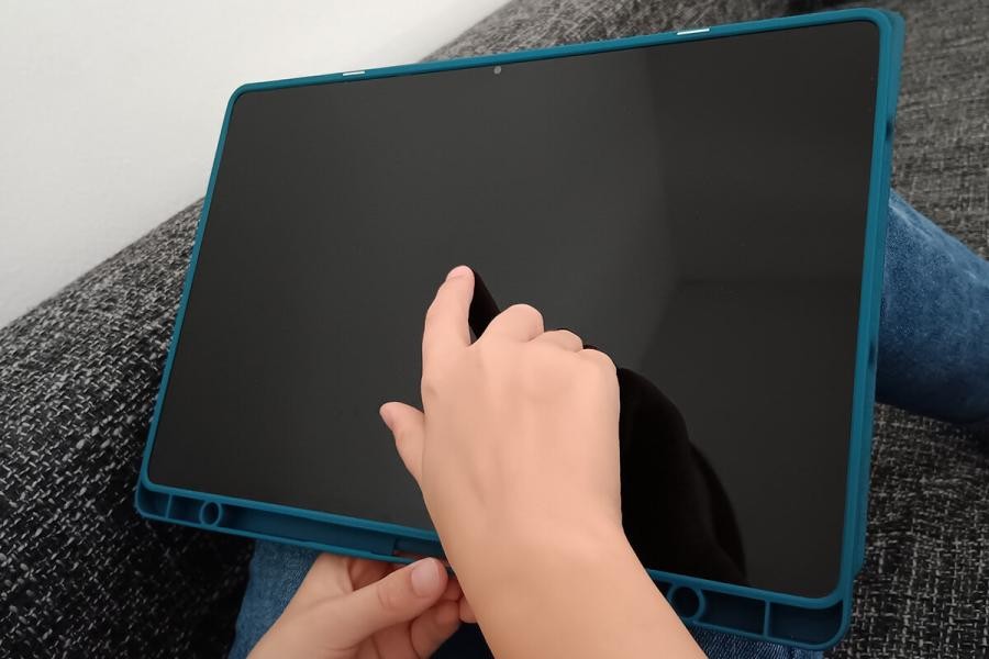 Eine Kinderhand tippt den im Ruhezustand befindlichen Bildschirm eines Tablets an