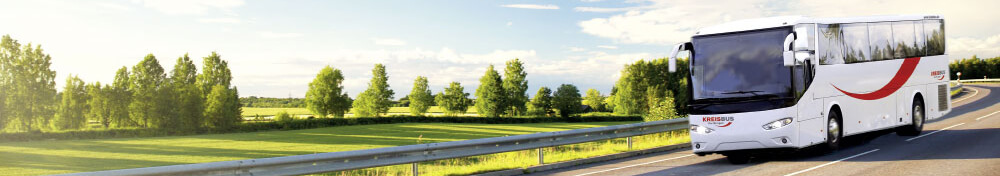 Bus mit dem Logo Kreisbus auf einer Straße in Wiesen und Baum-Landschaft