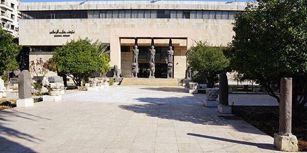 Eingangsbereich eines Museums mit vorgelagertem hellem Platz und Statuen am Eingang.