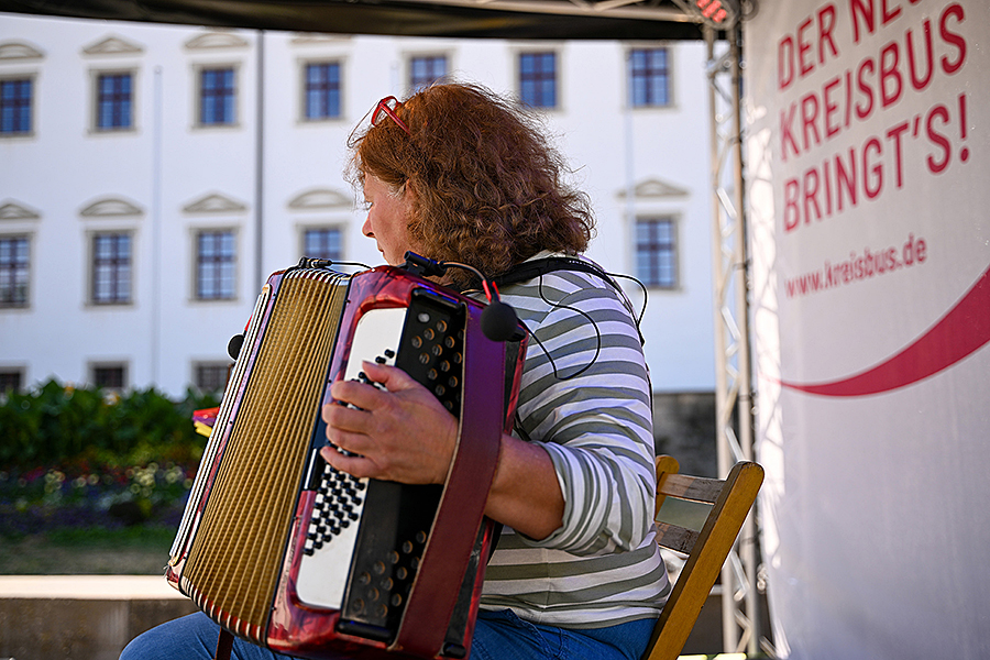 Musikerin mit Akkordeon spielt auf einem Stuhl auf der Bühne