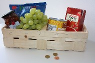 Spankorb gefüllt mit Weintrauben und haltbaren Lebensmitteln, davor Münzgeld