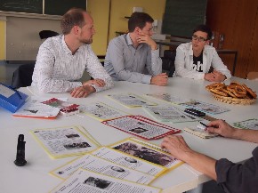 Eine Gruppe von jungen Menschen sitzt an einem Tisch mit Arbeitspapieren 
