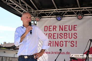 Der Erste Bürgermeister Thomas Weigel als Vertreter der Stadt Rottenburg spricht am  Mikrofon auf der Bühne, dahinter das Plakat "Der neue Kreisbus bringt's!"