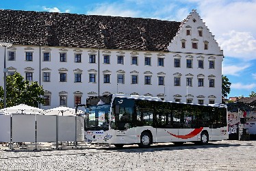 Großes Gebäude davor ein Kreisbus, erkennbar am geschwungenen Bogen des Logos  und Sonnenschirme