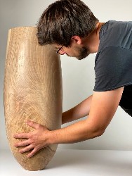 Felix Votteler stellt eine große Vase aus Holz auf.