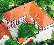 Luft-Bild, es zeigt ein rechtwinklig gebautes historisches Fachwerkgebäude mit zwei Gebäude-Flügeln und ein Neben-Gebäude