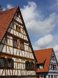 Zwei mit den Traufseiten nebeneinander stehende Häuser mit Satteldach, zu sehen sind die oberen Geschosse der Fachwerk-Giebel