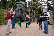 Eine Gruppe von jungen Leuten steht auf dem Gelände mit einem Wachturm und einer Holzkonstruktion des Konzentrationslagers in Natzweiler-Struthof